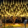A garden scene at night decorated with solar-powered meteor shower lights, a Christmas tree, and festive ornaments. Produktbild-Vorschau