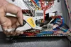 A hand is using a wire stripper tool on a bundle of wires inside an electrical panel. Anteprima dell’immagine prodotto