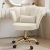 A beige velvet office chair with a scalloped back and a small lumbar pillow, placed in a well-lit room with a vanity table in the background. Voir les images du produit
