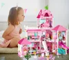 A young girl is playing with a large pink dollhouse. Voir les images du produit