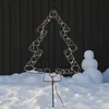 A lighted Christmas tree decoration stands in the snow in front of a dark wooden wall, with a snowman to the right. Produktbild-Vorschau