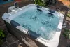 A hot tub filled with bubbling water, situated outdoors on a patio. Produktbild-Vorschau