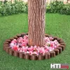 A tree trunk surrounded by pink flowers and a brown border, on a green lawn. Produktbild-Vorschau