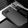 A smartphone case with a carbon fiber look is placed on a laptop keyboard, next to two pens. Produktbild-Vorschau
