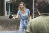 A woman playing table tennis outdoors with a man in the foreground. Produktbild-Vorschau