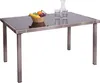 A rectangular poly-rattan table with a glass top, set against a white background. A fruit bowl, two glasses, and a carafe are placed on the table. Produktbild-Vorschau