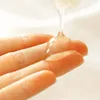 A close-up shot of a clear, viscous liquid being dispensed onto a person's fingers. Voir les images du produit
