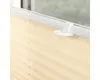 Close-up of a cream-colored pleated blind attached to a window frame with a white mounting bracket. Produktbild-Vorschau
