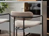 Close-up of a beige bar stool with a black metal frame, placed in a modern interior setting. Náhľad obrázku produktu