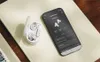 A pair of white AKG wireless earbuds in their charging case next to a smartphone displaying the AKG app. Anteprima dell’immagine prodotto