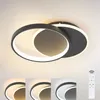 A modern LED ceiling light with two interlocking rings, shown against a white ceiling. Below the main product image are four smaller images demonstrating different light color temperatures, and a remote control. Produktbild-Vorschau