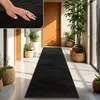 A hallway with a black runner rug, plants in baskets, and wooden doors. Produktbild-Vorschau
