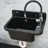 A black sink with a flexible chrome faucet mounted on a gray textured wall. Produktbild-Vorschau