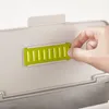 A hand is shown interacting with a green slotted insert on a gray lid of a compost bin. Náhled obrázku produktu
