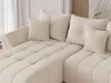 Close-up view of a beige sectional sofa with tufted cushions and throw pillows. Produktbild-Vorschau