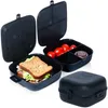 Three black lunchboxes are displayed against a white background. One lunchbox is closed, while the other two are open, one containing a sandwich and lettuce, and the other containing cherry tomatoes and a small dark item. Podgląd zdjęcia produktu