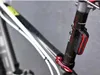A close-up shot of a bicycle's seat post with a red and black taillight attached. Podgląd zdjęcia produktu