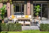 An outdoor patio setting with a sectional sofa, dining table, chairs, and plants. Produktbild-Vorschau