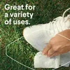 A hand is wiping a white sneaker with a white wipe on a grassy surface. Anteprima dell’immagine prodotto