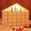 A wooden advent calendar shaped like a house, decorated with Christmas trees and small houses, illuminated by LED lights. Voir les images du produit