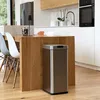 A modern kitchen with a stainless steel automatic trash can in the foreground, next to a wooden kitchen island with chairs. Produktbild-Vorschau