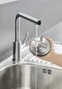 A hand holding a blender blade attachment under a running faucet in a kitchen sink. Voir les images du produit