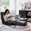 A woman is sitting on the floor reading a magazine next to a laptop on a portable table. Produktbild-Vorschau