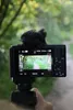 A hand holding a Sony ZV-1 II camera, recording a path through a forest. Produktbild-Vorschau