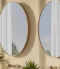 Two round mirrors with gold frames are mounted on a light beige wall above a shelf with plants and decorative items. Podgląd zdjęcia produktu