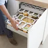 A person is reaching into a kitchen drawer filled with various food storage containers. Anteprima dell’immagine prodotto