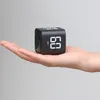 A hand holding a small black cube timer. Produktbild-Vorschau