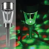 A split image showing a solar garden light in two different lighting conditions. The left side shows the light in daylight with subtle colored light projections, while the right side shows the light at night, projecting colorful lights onto a surface. Anteprima dell’immagine prodotto