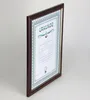 A framed certificate is shown at an angle against a light gray background. Produktbild-Vorschau