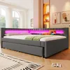 A modern bedroom with a grey upholstered bed featuring pink LED lighting and a green throw blanket. Produktbild-Vorschau
