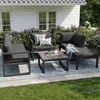 An outdoor patio set with seating and a coffee table, set against a white house and garden. Anteprima dell’immagine prodotto