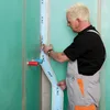 A man is applying a waterproofing tape to a wall in what appears to be a bathroom or wet room. Produktbild-Vorschau