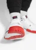 Close-up shot of a person wearing white Nike sneakers and white socks with a red logo. Náhled obrázku produktu