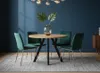 A round dining table with four green velvet chairs in a dining room setting. Produktbild-Vorschau