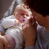 A person holding a sleeping baby with a pacifier. Produktbild-Vorschau