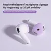 Two white and purple earbuds with purple silicone covers are shown on a light purple background. Voir les images du produit