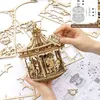 A person's hands are assembling a wooden carousel model, with instructions and other wooden pieces scattered around. Anteprima dell’immagine prodotto