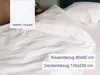 A close-up view of white bedding, including a pillow and duvet, with text overlays indicating product details. Produktbild-Vorschau
