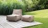 Outdoor patio with a bean bag chair and ottoman on a wooden deck, surrounded by grass and greenery. Produktbild-Vorschau