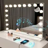 A vanity mirror with lights and Bluetooth speaker functionality is displayed on a white dresser, with makeup and a smartphone nearby. Produktbild-Vorschau