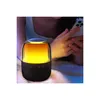 A person holding a smartphone next to a glowing Bluetooth speaker. Náhled obrázku produktu