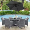 A patio dining set with chairs and a table under a large umbrella, next to a swimming pool. Produktbild-Vorschau
