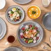 A top-down view of a table setting with plates of food, soup, and a cup of tea. Produktbild-Vorschau