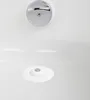 A close-up view of a white bathtub with a chrome drain cover and a white drain stopper with a chrome center. Voir les images du produit