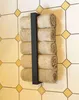 A black metal towel rack with rolled beige towels mounted on a tiled wall. Anteprima dell’immagine prodotto