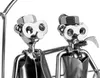 A close-up of two metal figures made from nuts and bolts, sitting on a swing. Anteprima dell’immagine prodotto